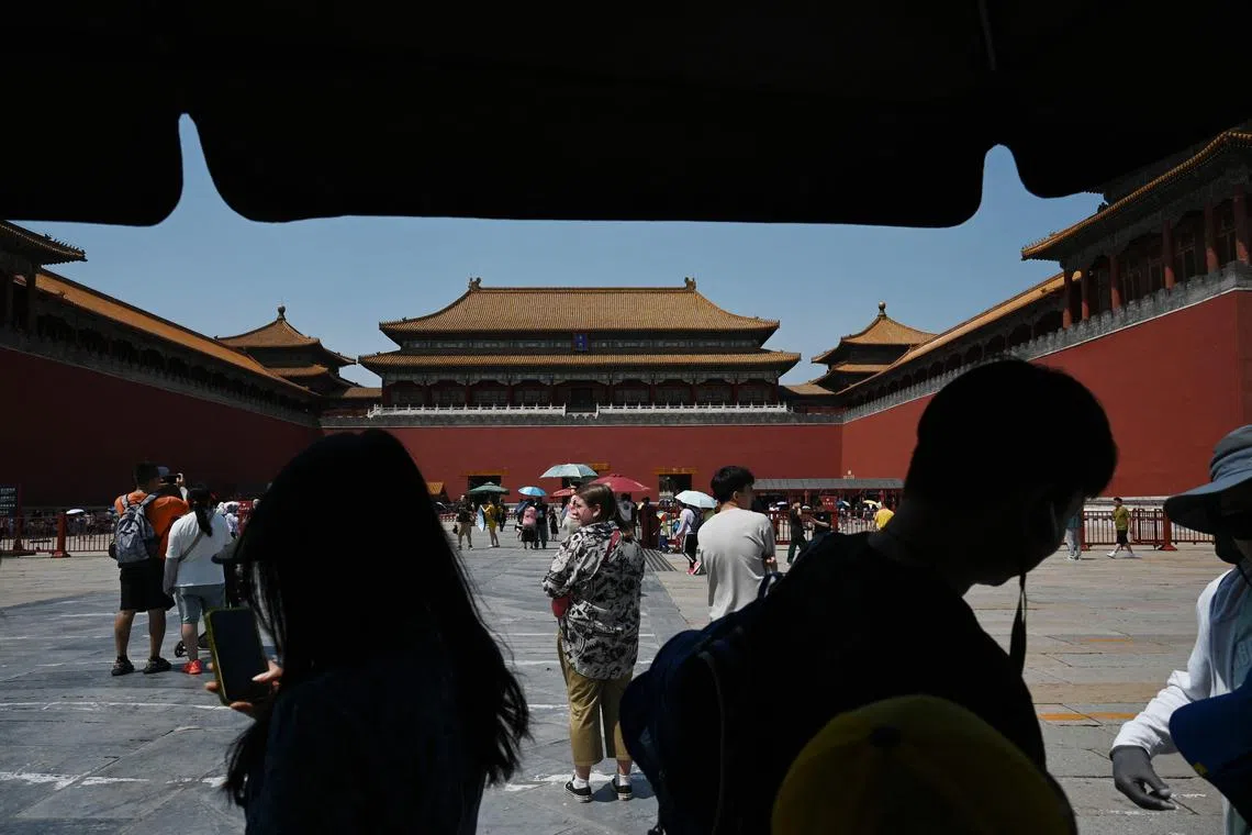 People shelter under an umbrella before visiting the Forbidden City during a heatwave in Beijing on June 24, 2023. Beijing recorded its third consecutive day of 40 degree Celsius weather, the first time since records began. (Photo by GREG BAKER / AFP)