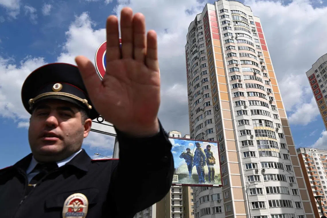 A police officer secures an area outside a damaged multi-storey apartment building after a reported drone attack in Moscow.