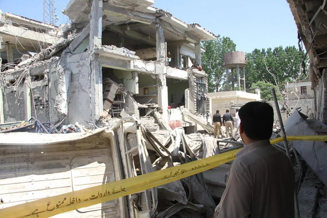 Pakistani security officials inspect the scene after two blasts rocked a counter-terrorism office in the Swat Valley, north-western Pakistan on Monday.