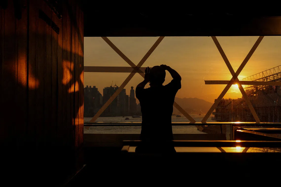 A shop worker taping a glass window in preparation for Typhoon Ragasa inside  a store in Hong Kong, China on Sept 22, 2025. 