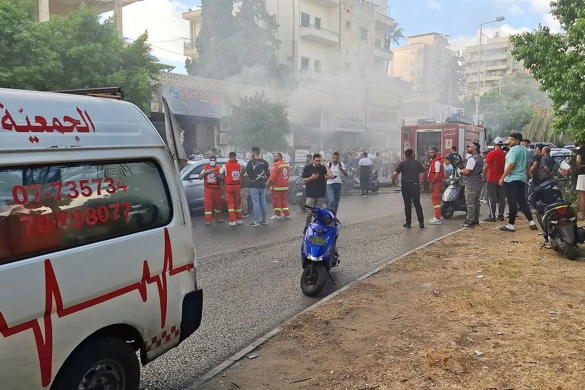 Smoke rises from a mobile shop as civil defence members gather in Sidon, Lebanon September 18, 2024. REUTERS/Hassan Hankir/File Photo