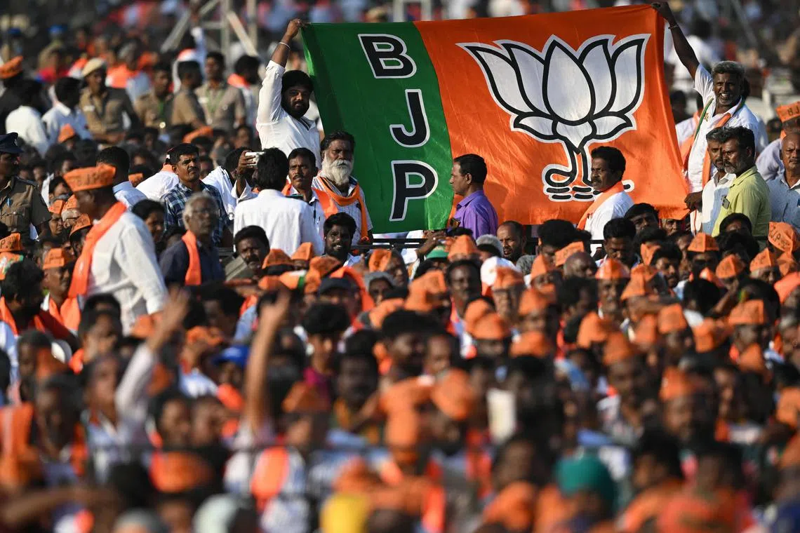(FILES) Bharatiya Janata Party (BJP) supporters hold a party flag during a public meeting attended by India's Prime Minister and party leader Narendra Modi in Chennai on March 4, 2024. Modi's popularity remains stratospheric a decade since he first swept to power, having successfully cast himself as the custodian of both India's rising global stature and the best interests of its majority faith. More than two dozen opposition parties hoping to unseat his Hindu-nationalist government at elections starting next month are campaigning jointly on a pledge to tackle rising economic distress. (Photo by R. Satish BABU / AFP)