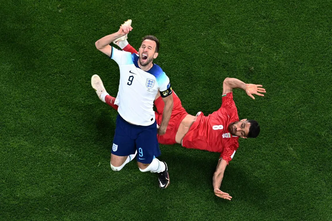 England's forward Harry Kane and Iran defender Morteza Pouraliganji collide during the Qatar 2022 World Cup Group B football match between England and Iran at the Khalifa International Stadium in Doha on Monday.