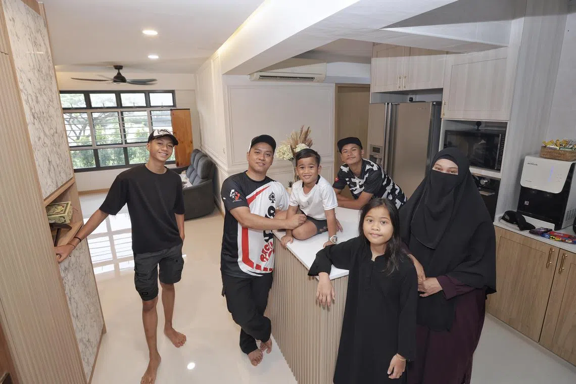 Business owner Azliana Ahmad (right), 38, her husband Suhaimi Jasim (second from left), 37-year-old driver, with their children (from left) Dani Syazwin, 17, Darwisy Alfarezel (seated on the kitchen island), five, Danny Airish (rear), 17, and Dania Emirsha (front), 10, in their new BTO flat at Sengkang East Drive on Dec 16, 2023. Profile of low-income rental flat family who is moving into their BTO flat after 8 years, and looking ahead to brighter days 
Story is on a new initiative which uplifted and empowered them to pursue their goals to improve their circumstances, such as taking courses and expanding their home based businesses.