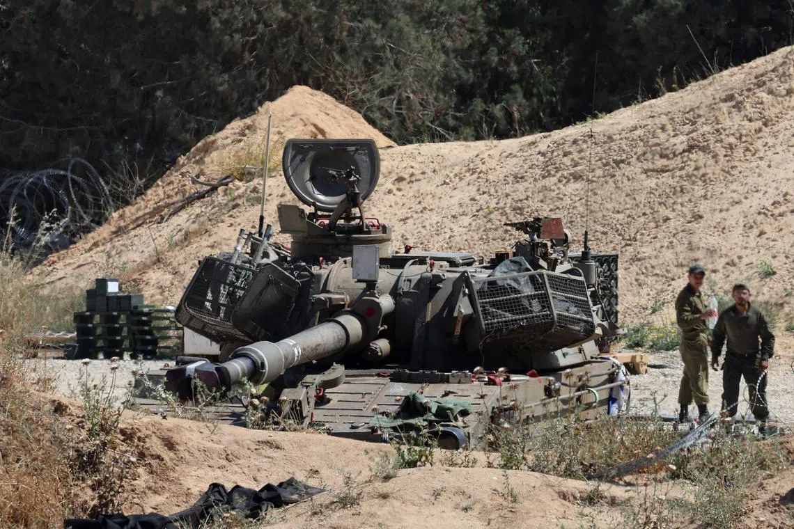 Soldiers stand near an Israeli army mobile canon at a position by Israel's border with the Gaza Strip, on May 6, 2025.
