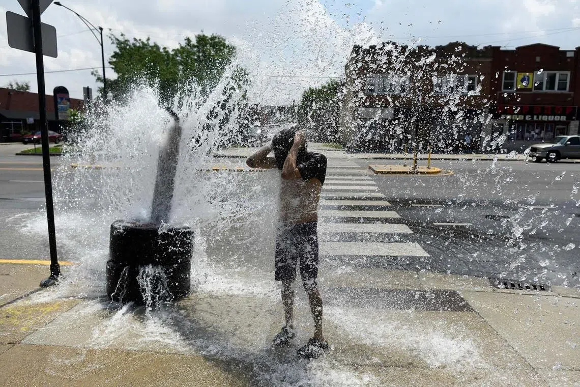 TOPSHOT - A person cools off with water from an open fire hydrant during a heat wave on the West Side of Chicago, Illinois, on July 2, 2026. Blistering temperatures and humidity gripped swaths of the United States on July 1, with the worst yet to come for the densely populated East Coast as the nation co-hosts the World Cup and prepares to celebrate its 250th birthday. "Heat dome" conditions -- in which high-pressure systems trap warm air like the lid on a pot -- persisted over the Midwest and South and were moving east, with some 46 million people under heat alerts. (Photo by OCTAVIO JONES / AFP)