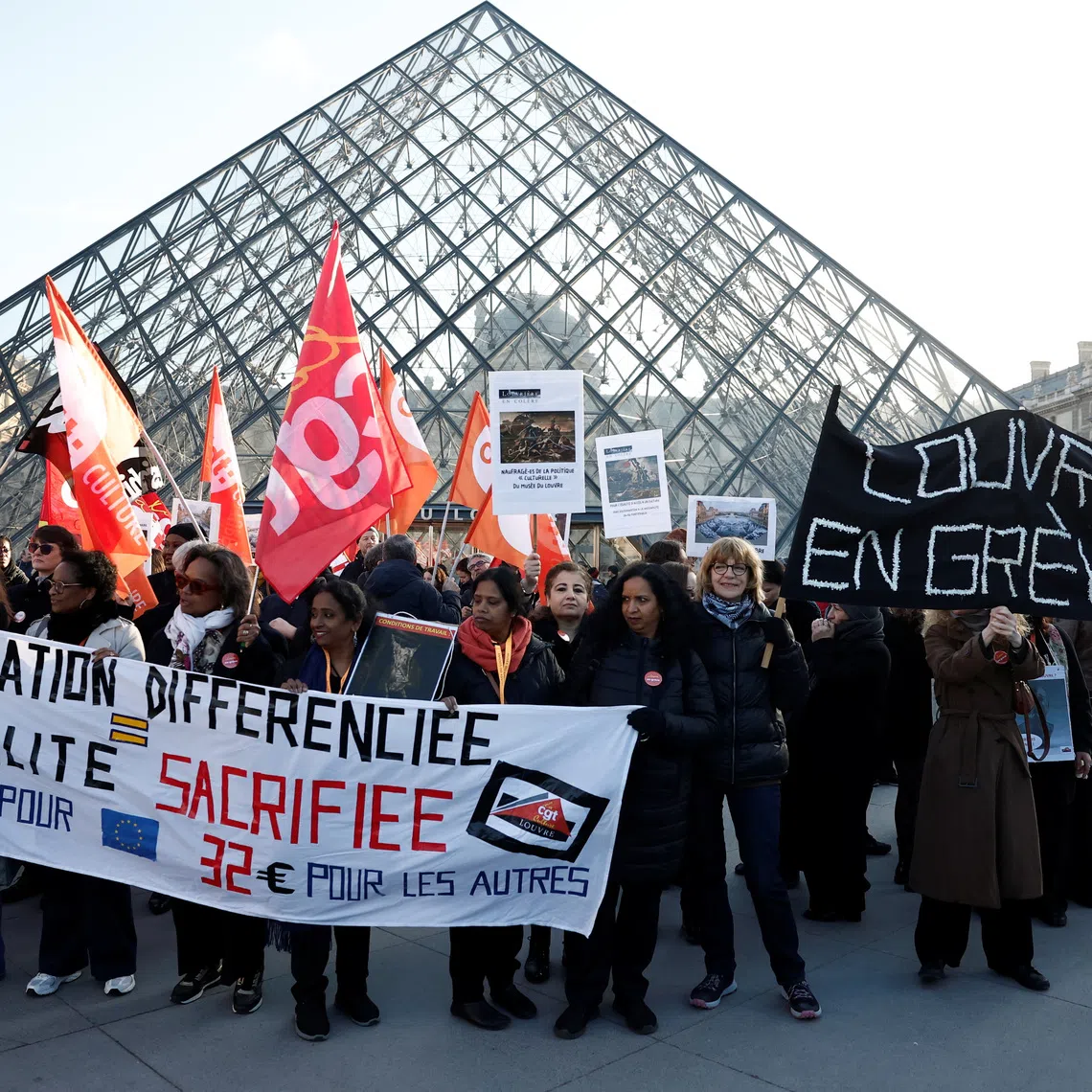 Louvre museum employees on strike hold a banner which reads \"Louvre on strike\" and CGT, CFDT Culture and Sud Solidaires labour unions flags near the glass Pyramid of the Louvre museum to protest their working conditions, the state of the museum's buildings and staffing issues, two months after a spectacular heist which saw thieves make off with jewels in broad daylight, in Paris, France, December 15, 2025. REUTERS/Benoit Tessier
