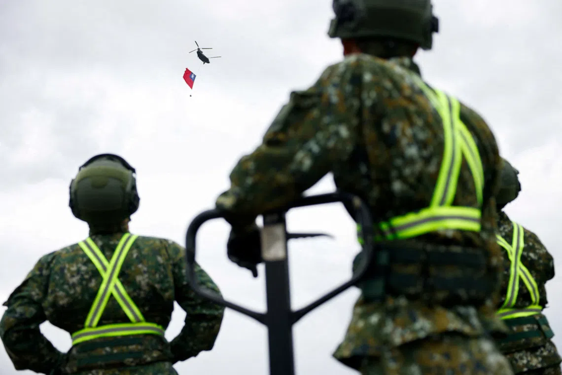 Taiwan military personnel watch as a US-made Chinook helicopter carries a giant Taiwanese flag during a rehearsal ahead of Taiwan's National Day celebrations in Taipei, Taiwan, October 6, 2026. REUTERS/Ann Wang