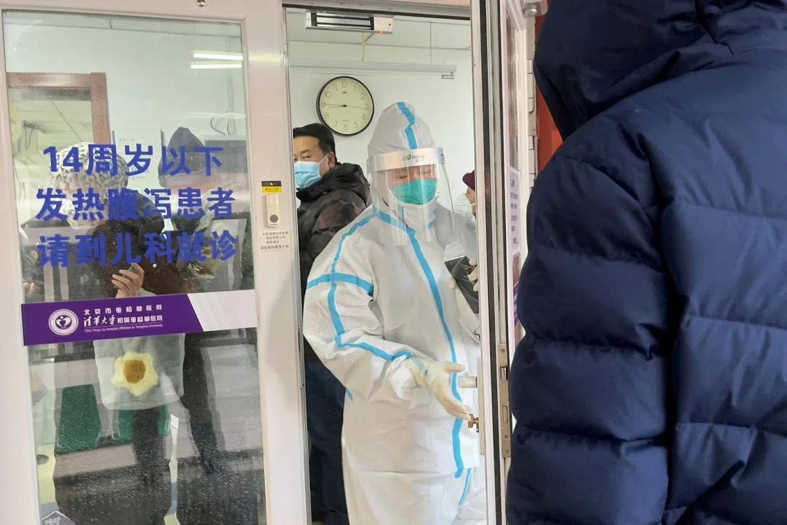 People line up next to a medical worker in a protective suit, at a fever clinic of a hospital amid the Covid-19 outbreak in Beijing, China, on Dec 15, 2022. 