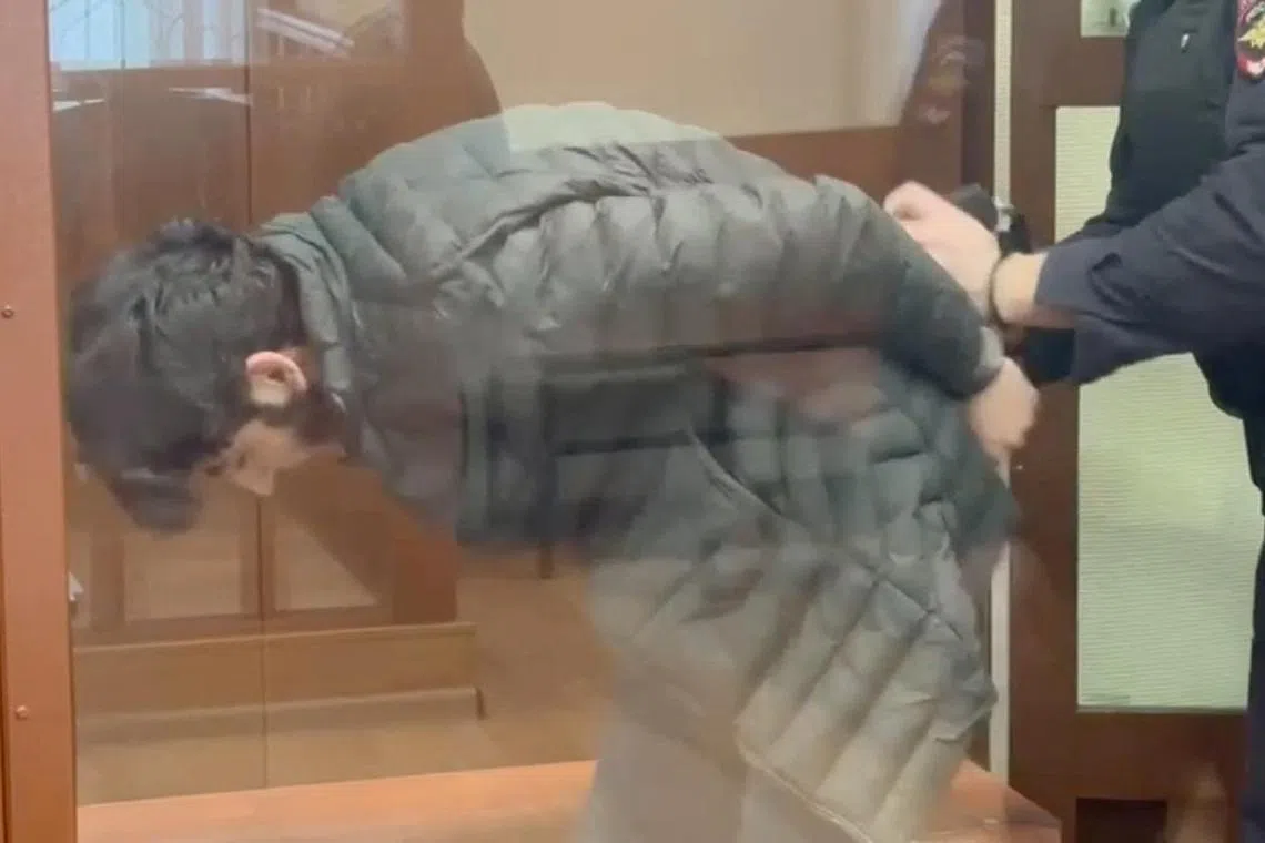 Nazrimad Lutfulloi, who was arrested in the course of investigations into the Crocus City Hall attack, is escorted behind a glass wall of an enclosure for defendants in a courtroom in Moscow in this still image from video released on March 29. 