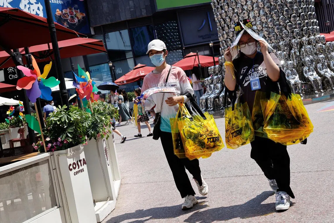 People shield themselves from the sun, as they walk amid a red alert for heatwave in Beijing, on June 23.