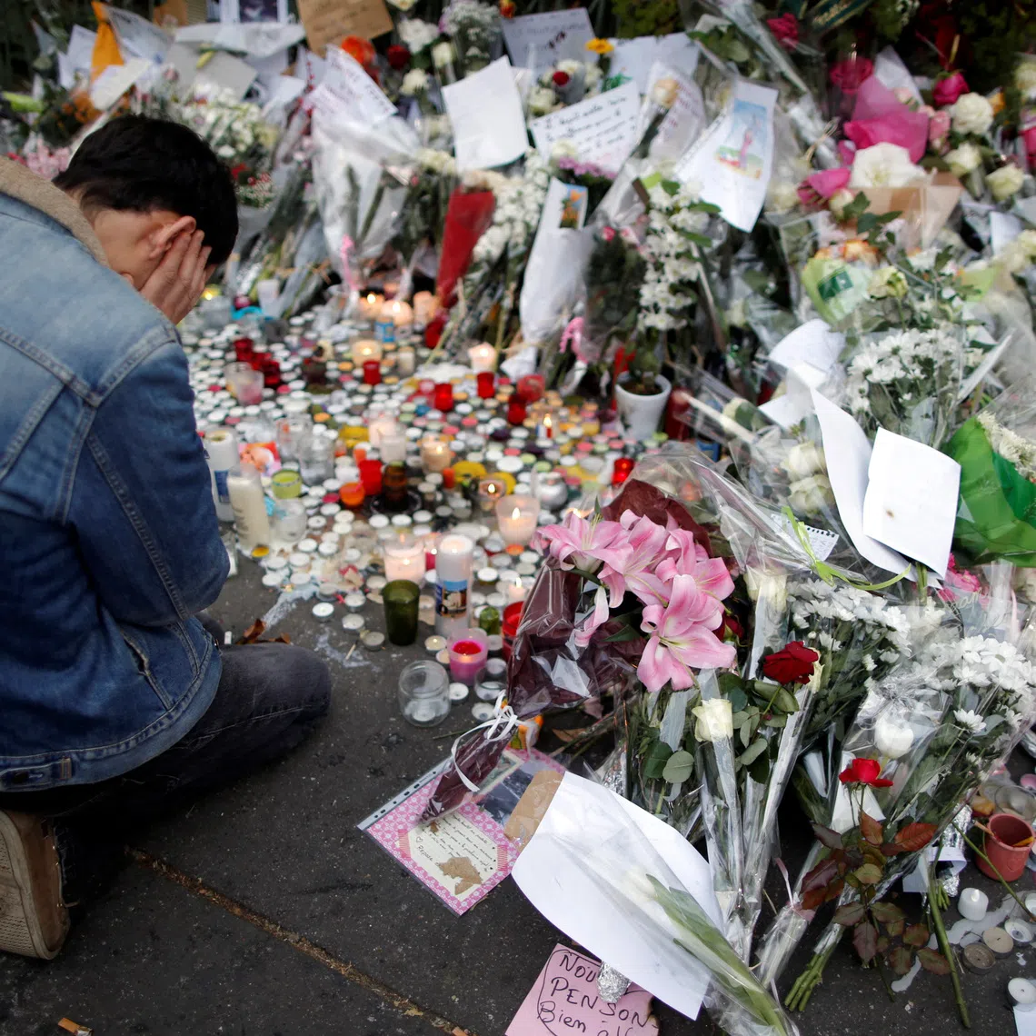 FILE PHOTO: A man kneels as he pays tribute to victims near the site of the attack at the Bataclan concert hall in Paris, November 16, 2015.    REUTERS/Christian Hartmann/File Photo