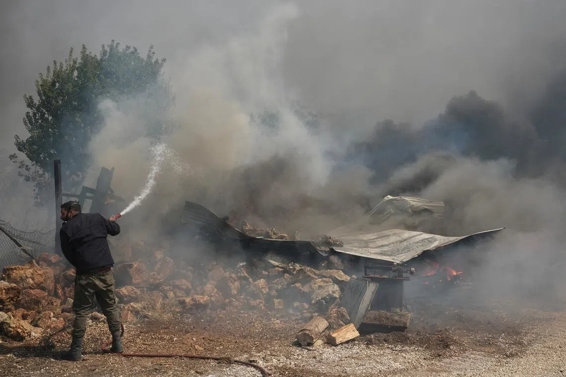 FILE PHOTO: A man tries to extinguish a fire burning a house as a wildfire burns in Nea Penteli, Greece, August 12, 2024. REUTERS/Elias Marcou/File Photo