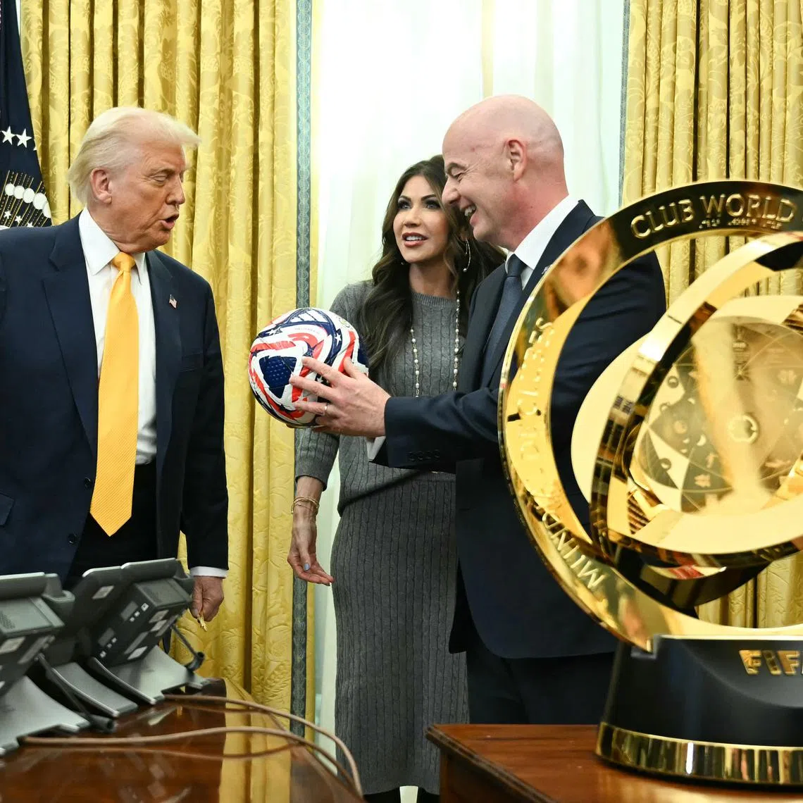 US President Donald Trump being shown the new Fifa Club World Cup trophy and official ball on March 7 by Fifa president Gianni Infantino, with US Secretary of Homeland Security Kristi Noem looking on.