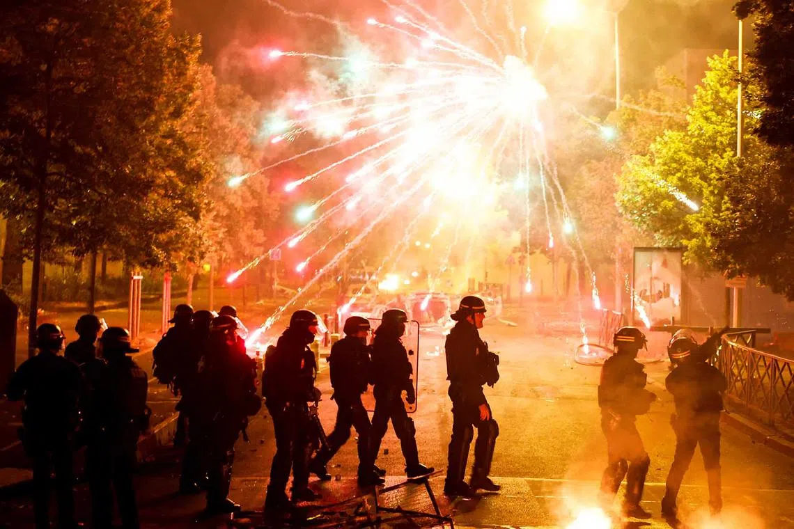 French police stand in position as fireworks go off during clashes with youth, after the death of Nahel, a 17-year-old teenager killed by a French police officer during a traffic stop, in Nanterre, Paris suburb, France, June 30.