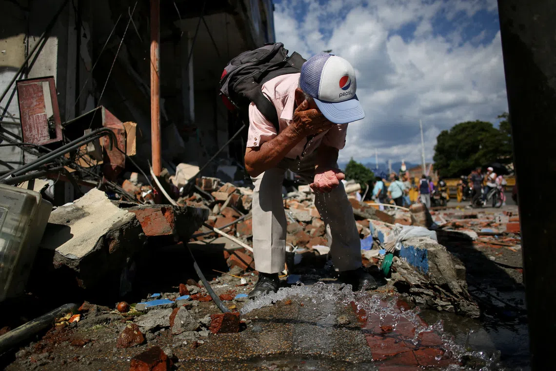 A man rinses his face among building debris after an earthquake, in Pereira, Colombia, on Aug 10.