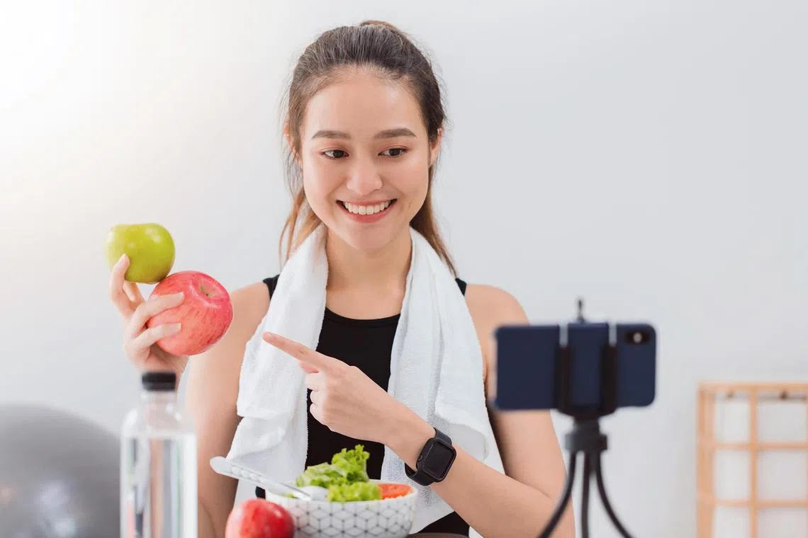 antrend - Beautiful asian woman healthy blogger is showing apple fruite and clean diet food. In front of the smartphone to recording vlog video live streaming at home.Fitness influencer on social media online.

Credit: ISTOCKPHOTO