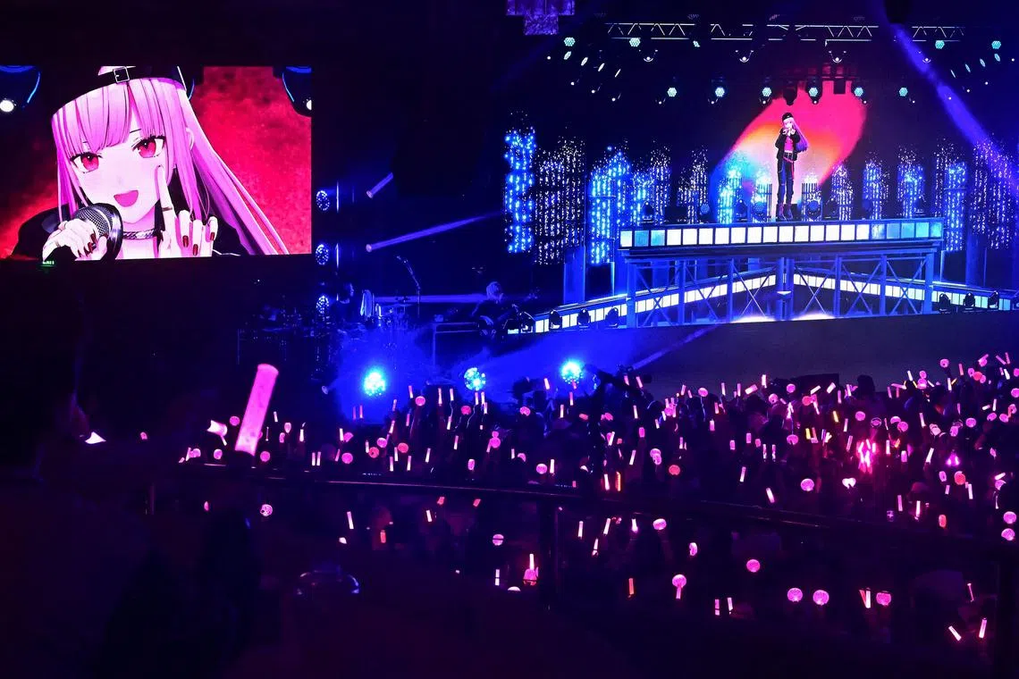 VTuber Mori Calliope performs for fans waving glowsticks and pensticks during a sold-out concert at the historic venue Hollywood Palladium in Hollywood, California on February 26, 2025. Fans waved glow sticks at an animated character on stage, having packed a sold-out Hollywood concert hall to see their virtual idol perform -- showcasing the global ambitions of Japan's "VTuber" subculture. (Photo by Frederic J. BROWN / AFP) / To go with 'JAPAN-US-ENTERTAINMENT-CULTURE-ANIME-VTUBERS,FOCUS' by Tomohiro Osaki, with Paula Ramon and Gilles Clarenne in Los Angeles