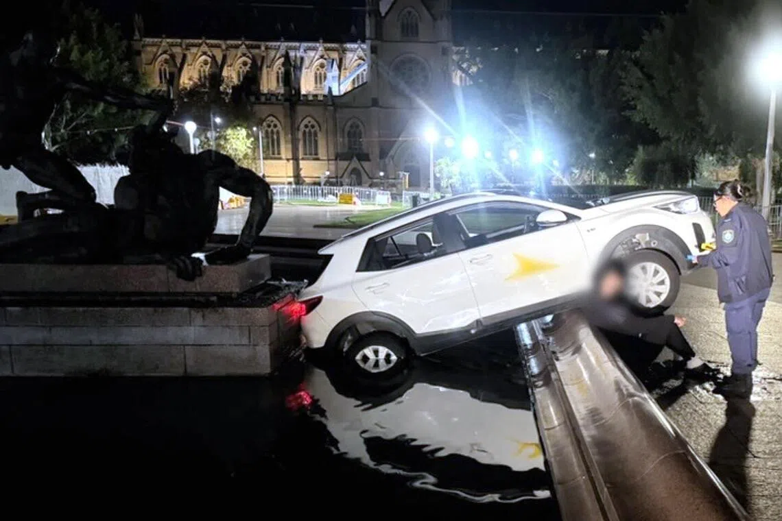 A police officer talks to a 21-year-old Frenchman who allegedly crashed an SUV car into the Archibald Fountain in downtown Sydney's Hyde Park on June 3. 