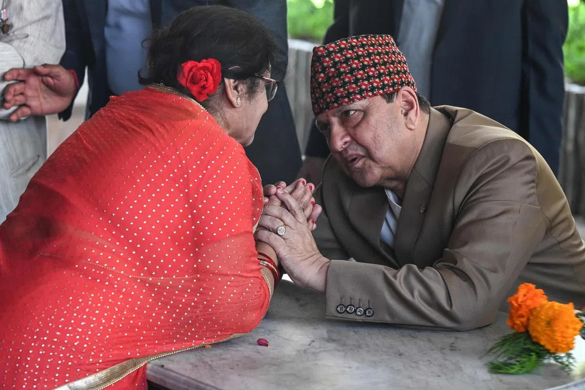Nepal's former King Gyanendra Shah (right) listens as a visitor wishes him happy birthday at his residence in Kathmandu on July 7, 2025.  