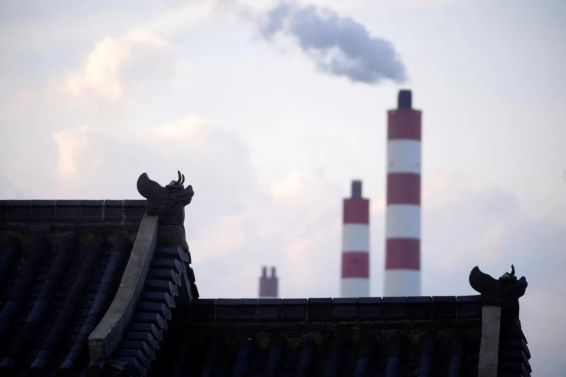FILE PHOTO: Chimneys of a coal-fired power plant are seen behind a gate in Shanghai, China, October 21, 2021. REUTERS/Aly Song/File Photo