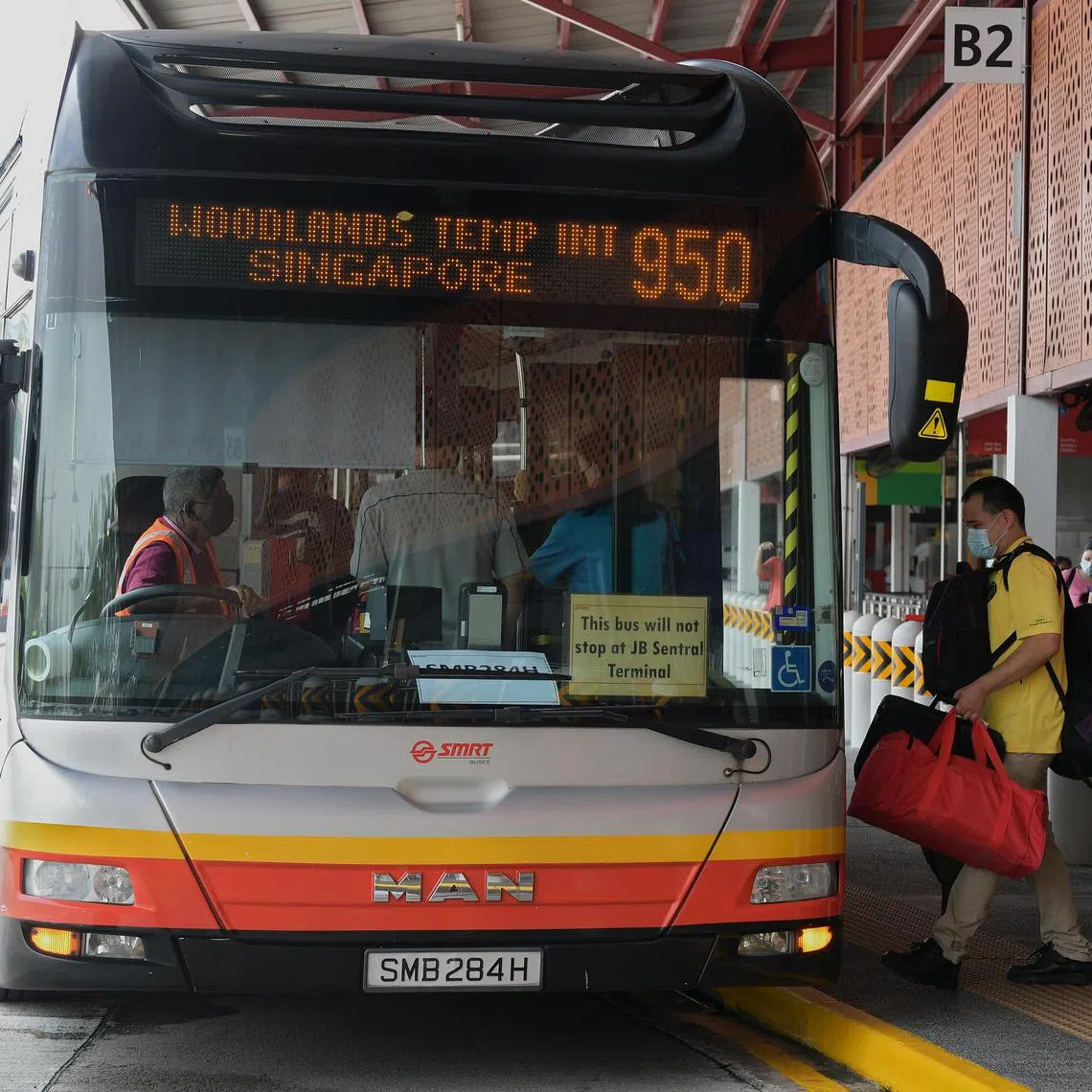 Commuters boarding service 950 at Woodlands Temporary Bus Interchange as cross-border bus services between Singapore and Malaysia resumed on 1 May 2022. Such bus services had been suspended since 2020, when the Covid-19 pandemic forced the two countries to close their land borders.