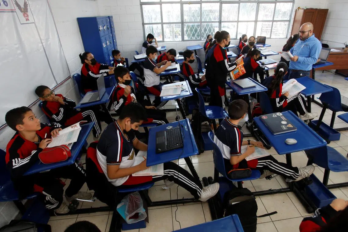 High school students pedal on a bike desk, as part of a programme to improve physical health and increase concentration during classes.