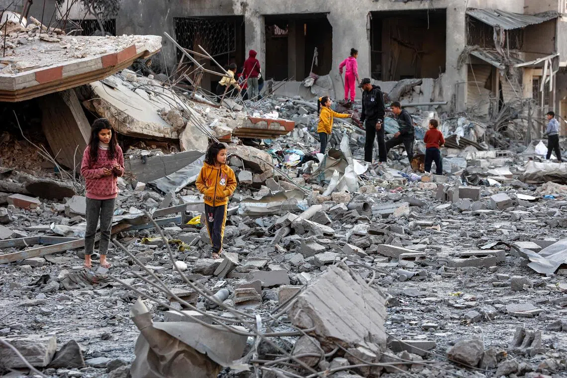 Children walk through debris and rubble at the site of Israeli bombardment on a residential block in Jalaa Street in Gaza City on Jan 14.