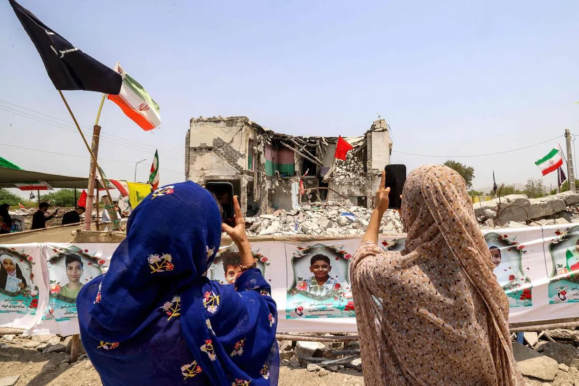 People film with their phones the destroyed Shajareh Tayebeh primary school in Minab.