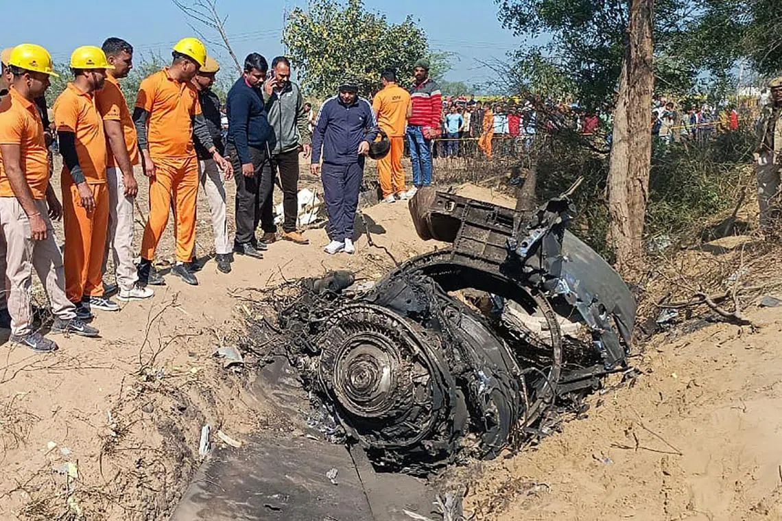 This handout photograph taken on Jan 28, 2023 and released by the Rajasthan State Disaster Response Force (SDRF) shows local rescue authorities and military officials inspecting wreckage of a crashed aircraft in the Bharatpur district.