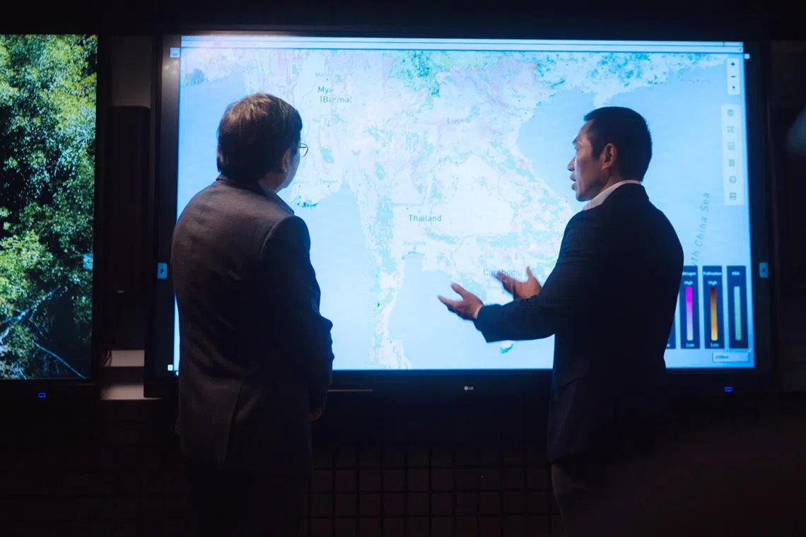 Professor Koh Lian Pin, the associate vice-president and chief sustainability scientist at NUS (right), demonstrating the capabilities of the NUS Decision Theatre to Professor Sun Yeneng, dean of the NUS Faculty of Science.