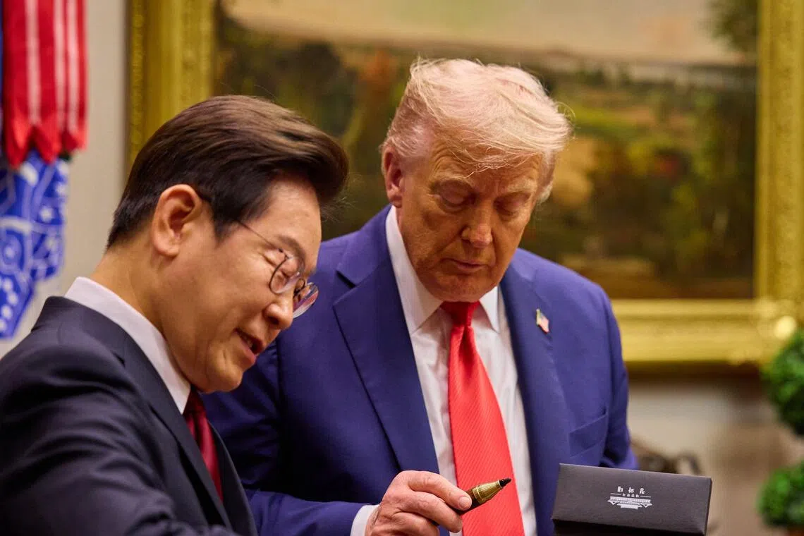 US President Donald Trump (R) looks at a handcrafted wood pen as South Korean President Lee Jae Myung (L) signs a guest book with the fountain pen before entering the Oval Office for their talks at the White House in Washington, DC, on August 25, 2025. The first summit between US President Donald Trump and his South Korean counterpart Lee Jae Myung in Washington produced an unexpected outcome: a surge in shares of a South Korean penmaker. (Photo by YONHAP / AFP) / - South Korea OUT / NO ARCHIVES -  RESTRICTED TO SUBSCRIPTION USE