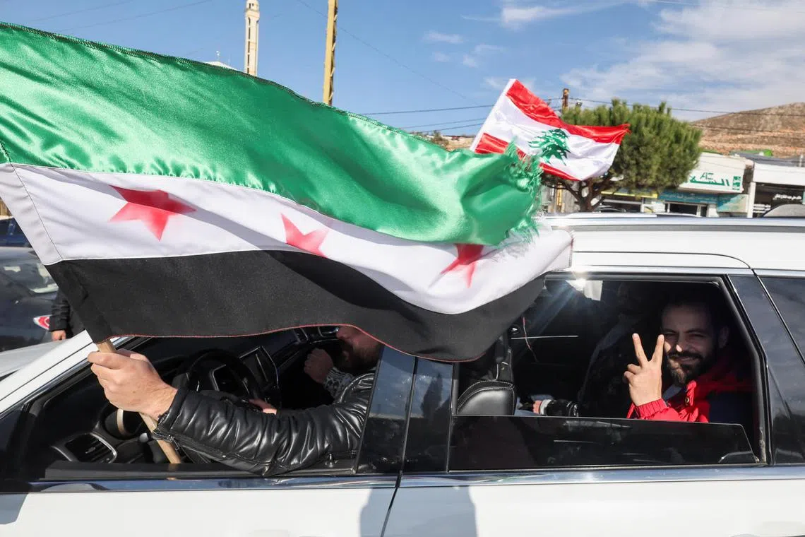 People celebrate from a vehicle while carrying a Syrian opposition flag and a Lebanese flag at Masnaa Border Crossing, after Syrian rebels announced that they have ousted President Bashar al-Assad, Lebanon, December 8, 2024. REUTERS/Amr Abdallah Dalsh  
