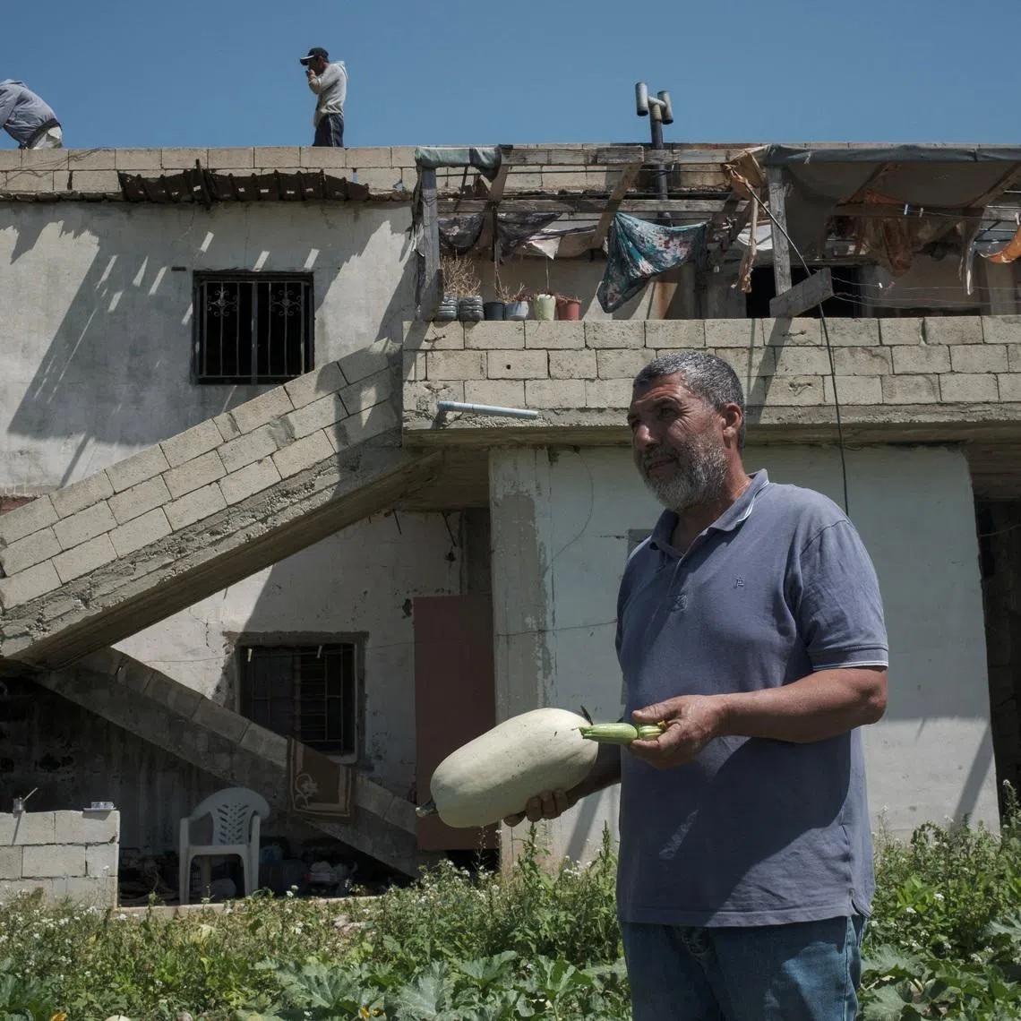 FILE PHOTO: Farmer Abu Hassan Issa holds a zucchini and other produce on a field in front of his house, amid a temporary ceasefire between Lebanon and Israel, in the village Ras El Ain, near Tyre, southern Lebanon, April 27, 2026. REUTERS/Marko Djurica/File Photo
