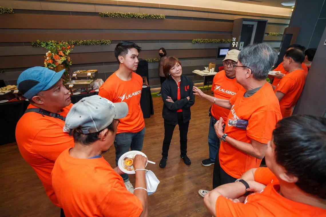 Mr Javier Wong, Lalamove Singapore's senior manager of driver operations (third from left), and Ms Cham Hui Fong, NTUC deputy secretary-general (centre), speaking to delivery drivers who use Lalamove for work, at the signing of a new pact between the logistics firm and the National Delivery Champions Association.