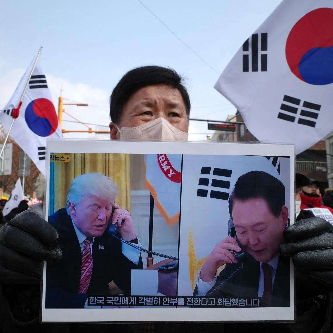 A supporter of impeached South Korean president Yoon Suk Yeol holds a placard of Yoon (R) and incoming US president Donald Trump (L) that translates as “He responded by sending his special regards to the people of South Korea”, during a rally near his residence in Seoul on January 6, 2025. South Korean investigators trying to arrest suspended President Yoon Suk Yeol have asked for an extension to the warrant that expires on January 6, with the embattled leader holed up in his residence. (Photo by Anthony WALLACE / AFP)