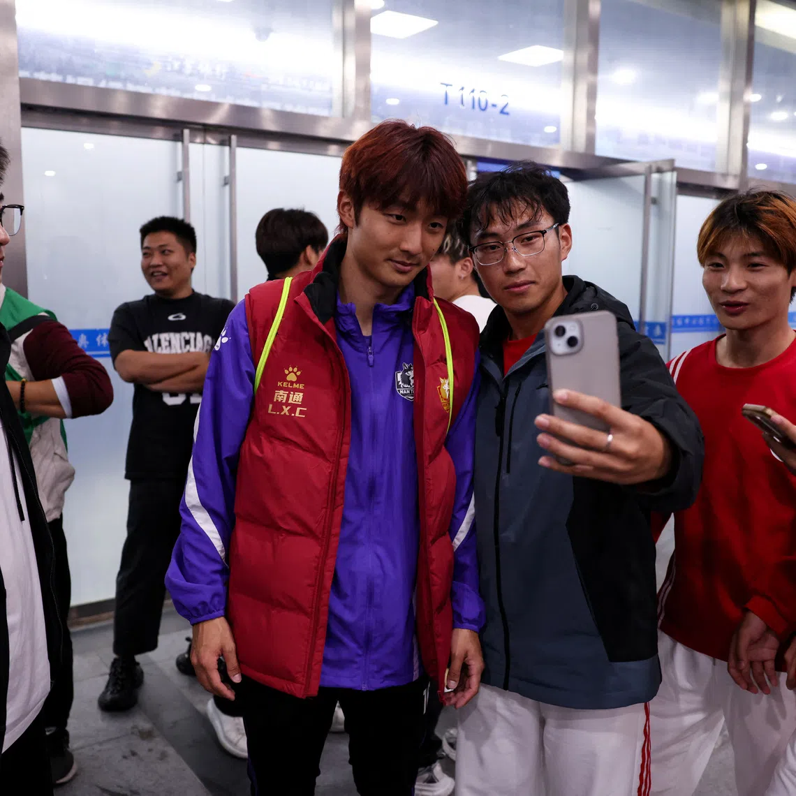 Volunteers take selfies with Nantong team's captain Li Xiancheng after his training, before the 2025 Jiangsu Football City League final, also known as Jiangsu Super League (JSL), at Nanjing Olympic Sports Center in Nanjing, Jiangsu province, China October 31, 2025. REUTERS/Tingshu Wang