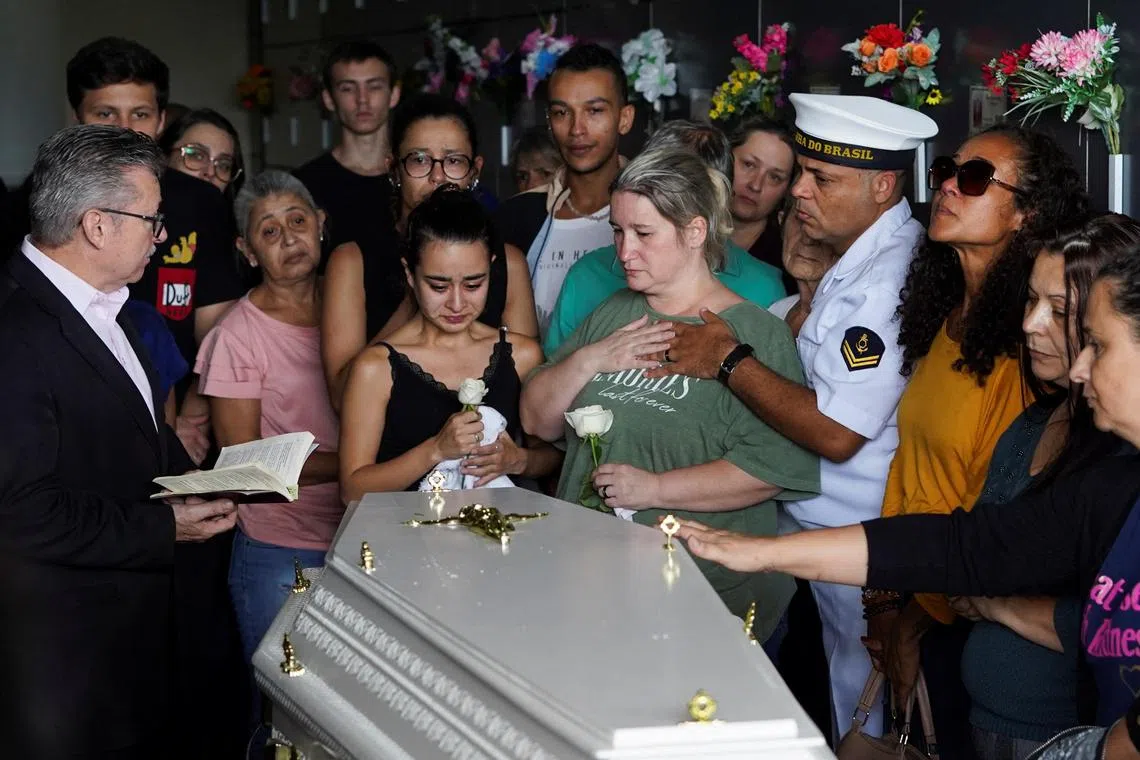 The parents of five-year-old Bernardo Cunha Machado stand alongside his coffin, during a wake in Blumenau, Brazil.