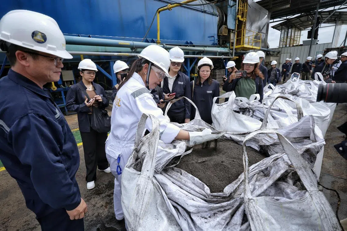 Mencast sales and business development manager Irni Masnita Mohamed Anis (in white), 48, showing a bag of treated sand to members of the media at the treatment facility in Mencast Offshore and Marine Pte Ltd on June 21, 2024. 