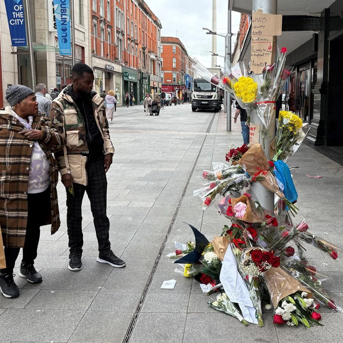 People stand near flowers laid outside a department store on Henry Street where a Congolese-born man, Yves Sakila, was restrained by security guards last week and later pronounced dead in hospital, in Dublin, Ireland, May 20, 2026. REUTERS/Conor Humphries