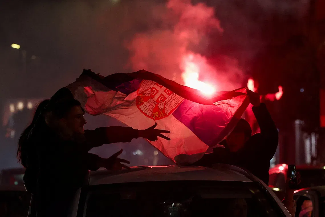 Image 4: People hold a Serbian flag as supporters of the electoral list "Student List - Students Win" celebrate following the first results of the parliamentary election in Belgrade, Serbia, October 25, 2026. REUTERS/Zorana Jevtic