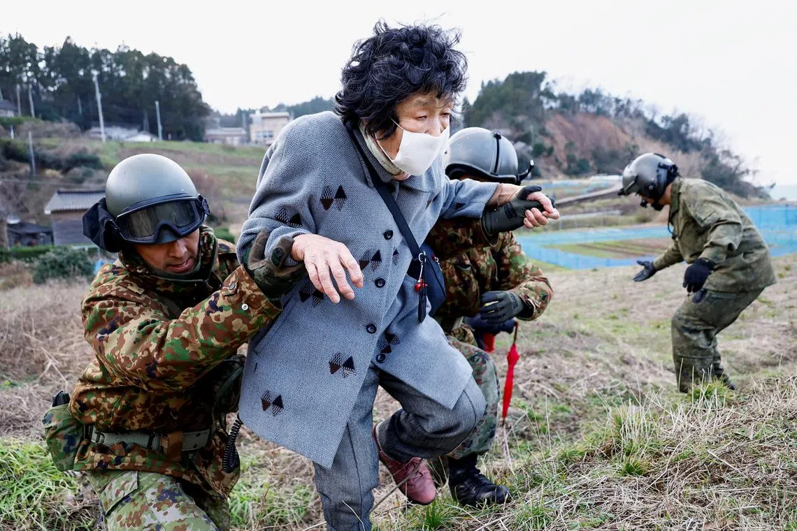 Residents in Fukamimachi, a village isolated after the earthquake, are helped by members of Japan Self-Defense Forces (JSDF) as they head to a rescue helicopter, in Wajima, Ishikawa Prefecture, Japan, Jan 6, 2024. 
