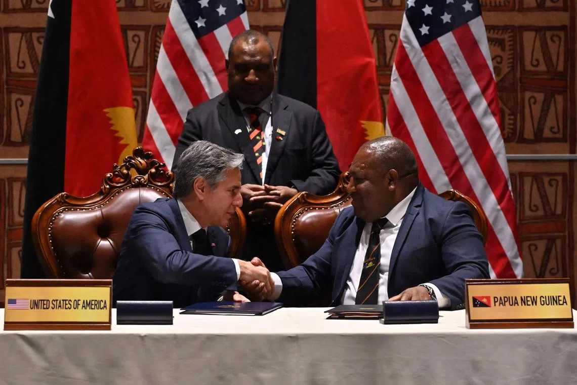 (FILES) US Secretary of State Antony Blinken (L) and Papua New Guinea’s Defence Minister Win Bakri Daki (R) shake hands after signing a security agreement as Papua New Guinea’s Prime Minister James Marape (C) looks on during the Forum for India-Pacific Islands Cooperation at APEC Haus in Port Moresby on May 22, 2023. The US military can develop and operate out of bases in Papua New Guinea, according to a landmark security pact that is part of Washington's efforts to outflank China in the Pacific. (Photo by ADEK BERRY / AFP)