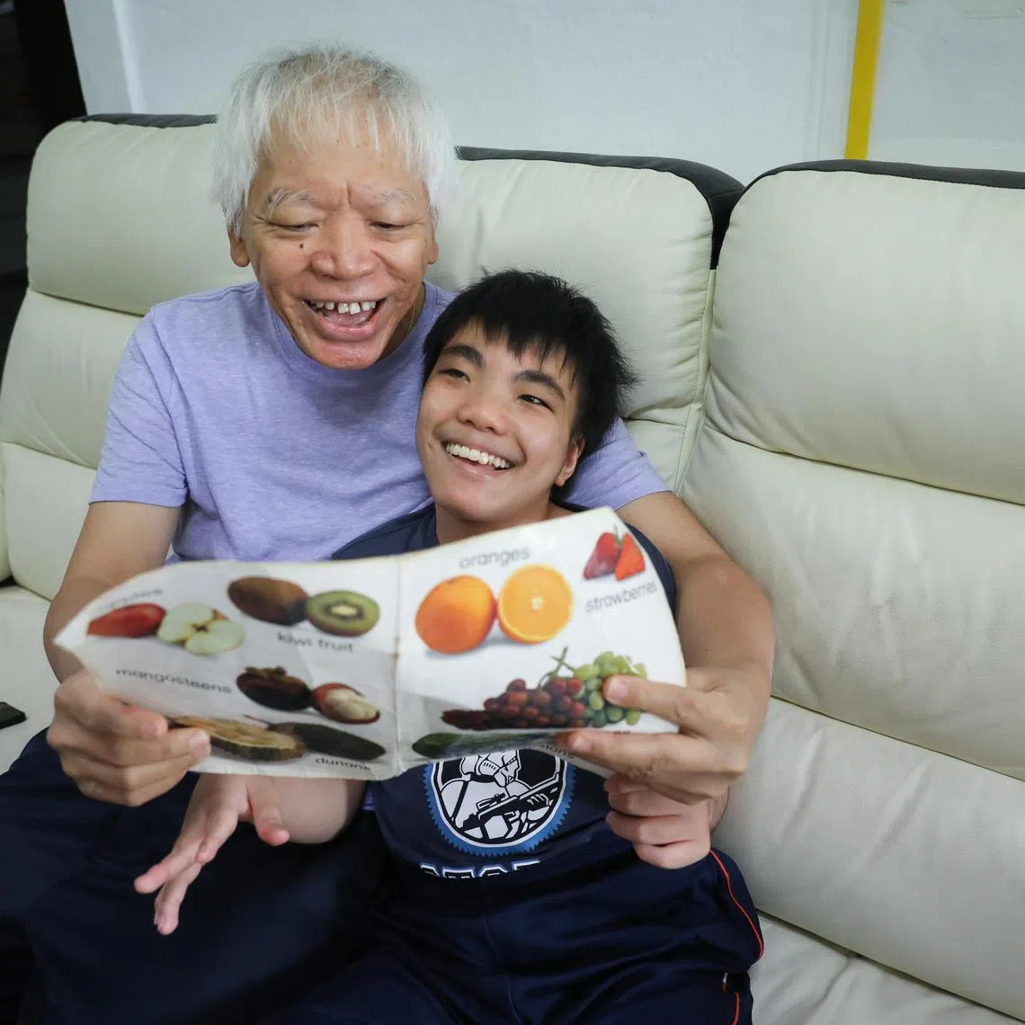 Mr Ben Phua, 69, wishes he had more time to read to his special needs son,  Zai Quan, 14, but as the boy's sole caregiver, he has too many chores to manage every day. ST PHOTO: TARYN NG