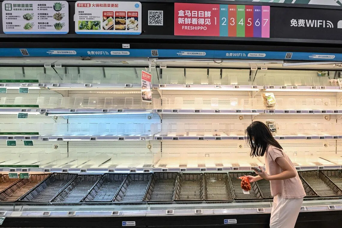 A woman buys groceries as empty shelves are seen at a supermarket in Shenzhen, in southern China's Guangdong province, on September 22, 2025, ahead of the landfall of the Super Typhoon Ragasa. The Chinese city of Shenzhen began preparing to evacuate 400,000 people while residents of the northern Philippines sought shelter from gale-force winds on September 22 as Super Typhoon Ragasa continued on a collision course with southern China. (Photo by Adek BERRY / AFP)