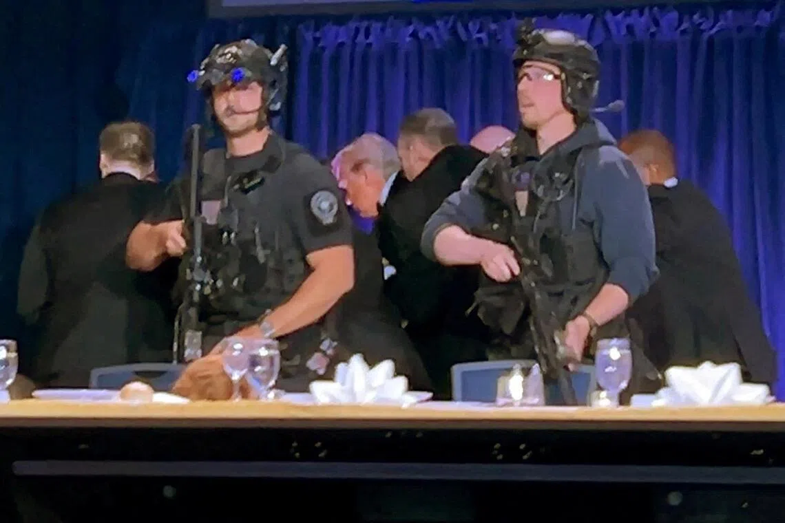 US President Donald Trump being escorted out after a man opened fire with a shotgun on security personnel outside the room, during the White House Correspondents' Association dinner in Washington DC.
