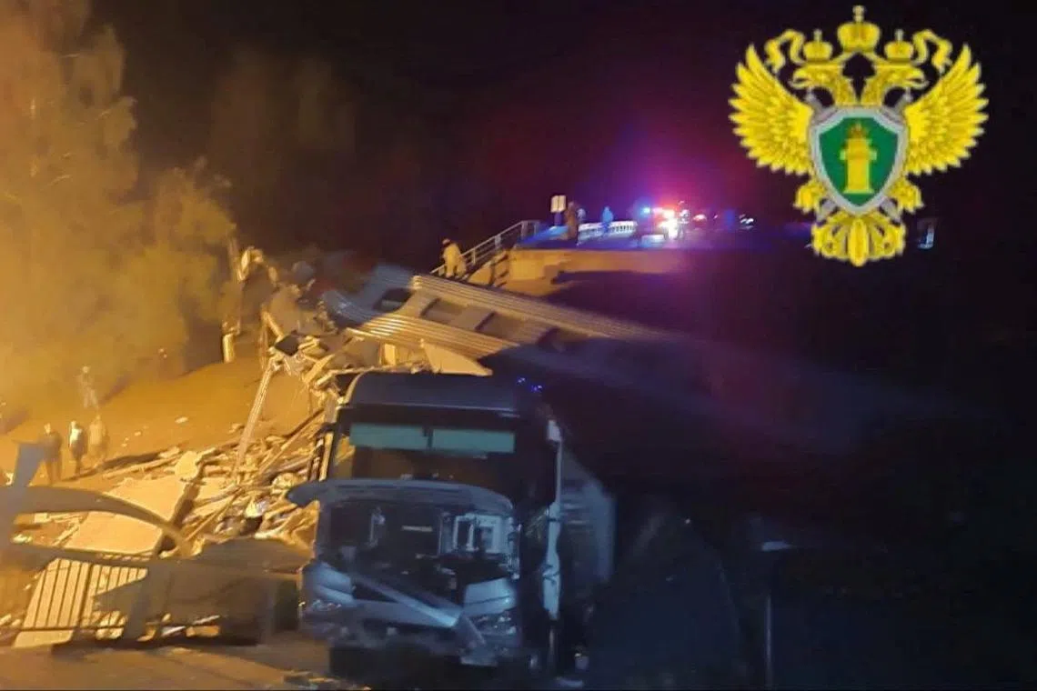 A view shows a damaged bus and a train carriage at the scene, after a road bridge collapsed onto railway tracks in the Bryansk region, Russia.