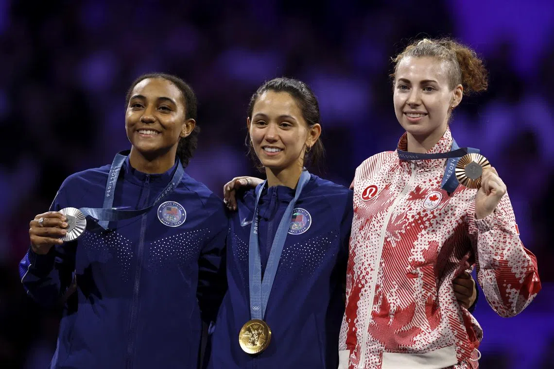 Paris 2024 Olympics - Fencing - Women's Foil Individual Victory Ceremony - Grand Palais, Paris, France - July 28, 2024. Gold medalist Lee Kiefer of United States celebrates with silver medalist Lauren Scruggs of United States and bronze medalist Eleanor Harvey of Canada on the podium after winning. REUTERS/Albert Gea