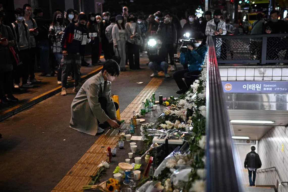 A man pouring a glass of an alcoholic beverage, in tribute to those who were killed in a Halloween crowd crush that took place the night before in a nearby alleyway in the popular district of Itaewon in Seoul on Oct 30, 2022.