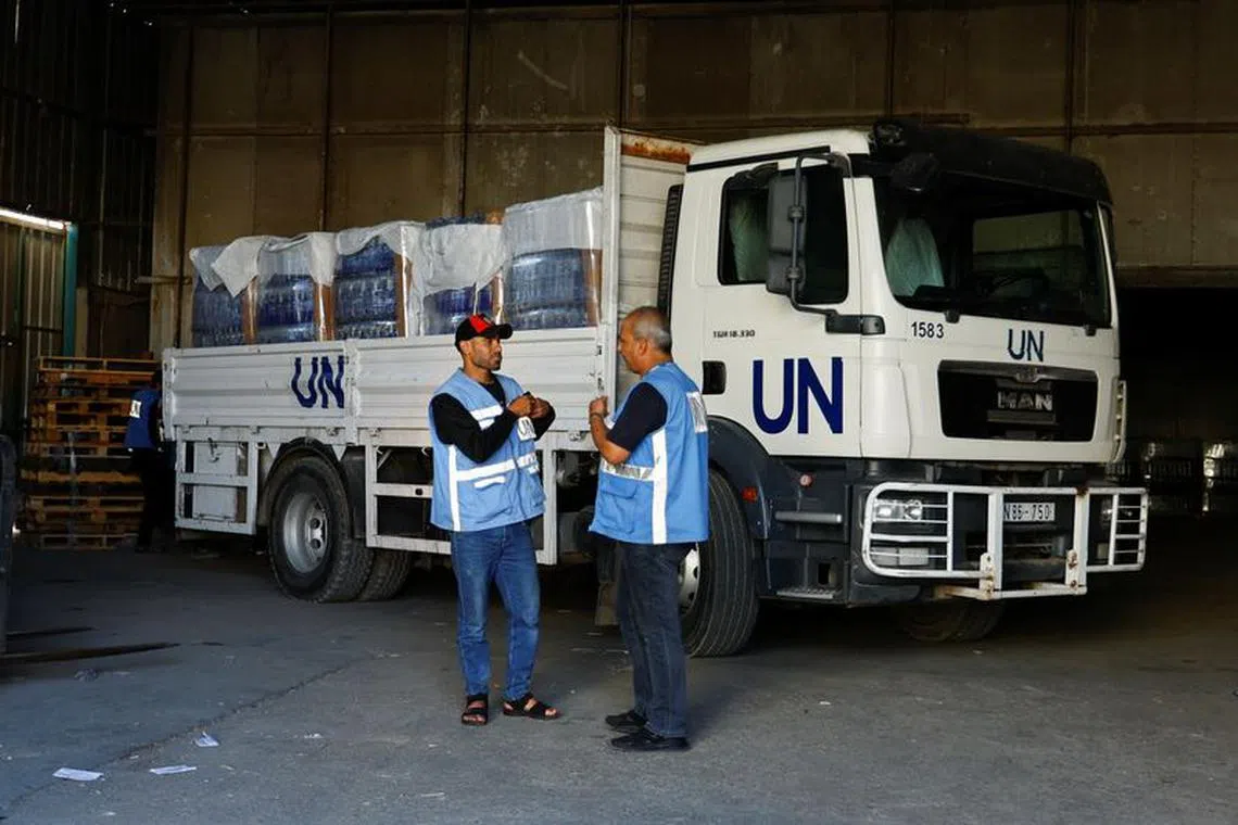 Workers stand by a United Nations vehicle, while sorting aid to be distributed to Palestinians, as the conflict between Israel and Palestinian Islamist group Hamas continues, at a United Nations-run facility, in Khan Younis in the southern Gaza Strip, October 26, 2023. REUTERS/Ibraheem Abu Mustafa